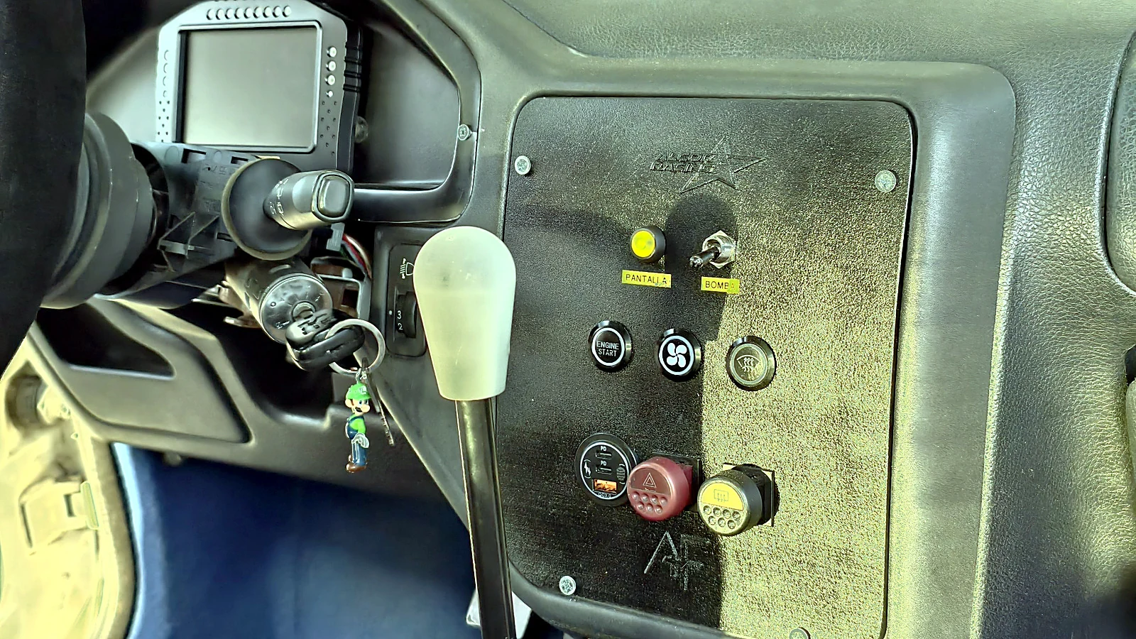 Panel de consola central impreso en 3D montado en el Peugeot 106 de ALCOR Racing, con los ocho mandos instalados y etiquetados y la pantalla de datos al fondo